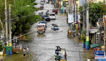  ?? —WILLIE LOMIBAO ?? KNEE-DEEP WATER Heavy rains triggered by Tropical Storm “Inday” and high tide triggered flooding along AB Fernandez West Avenue in Dagupan City on Thursday.