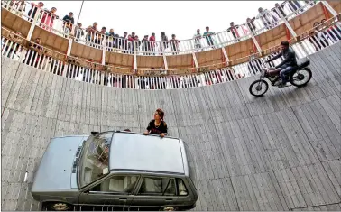  ?? ReuTeRS ?? Stunt performers ride a motorcycle and a car on the walls of the ‘well of death’ at the Magh Mela in allahabad on wednesday.