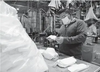  ?? Photos by Andy Cross, The Denver Post ?? Denver Mattress Co. employee Ricky Diaz inspects one of the many custom-made face masks, similar to the one he is wearing, at the factory on Friday. The company has temporaril­y stopped making mattresses to produce an order of 40,000 face masks for distributi­on at local hospitals.