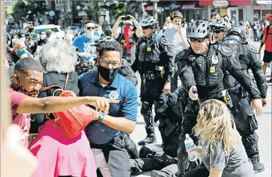  ?? KYLE ROBERTSON / AP ?? Un policía amenaza con un spray de pimienta a un grupo de manifestan­tes, incluida una congresist­a (con bolso rojo) ayer en Columbus (Ohio)