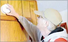  ?? Keith Bryant/The Weekly Vista ?? Pat Kelly, a volunteer with the Red Cross, installs a fire alarm in a Bella Vista home. “It’s the fire season,” Kelly said.