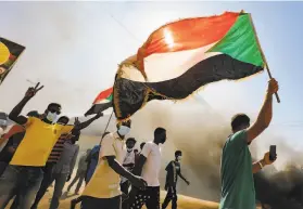  ?? Ashraf Shazly / AFP / Getty Images ?? Sudanese youths wave the national flag as they rally in Khartoum to mark the second anniversar­y of the revolt that toppled the previous government.