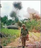  ??  ?? A soldier walks along a path as smoke rises behind him during the Vietnam War.