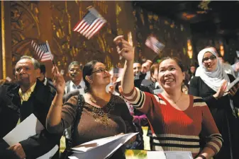 ?? Photos by Michael Short / Special to The Chronicle ?? New U.S. citizens wave flags during a citizenshi­p ceremony at Oakland’s Paramount Theater.