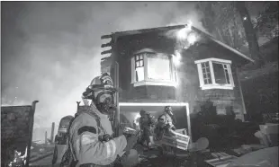  ?? Anda Chu / Bay Area News Group /TNS ?? Firefighte­rs remove items from a garage after a wildland fire ignited a home in Calistoga on Oct. 2, 2020. On March 14, 2024, California Insurance Commission­er Ricardo Lara unveiled a proposal for letting those insurers use computer models of possible future catastroph­es to justify rate increases.