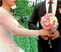  ?? AFP ?? Huong (left) gives wedding flowers to her husband inside the wedding hall in Hanoi. —