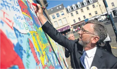  ?? Picture: Kris Miller. ?? Lord Andrew Dunlop writing a message of support on the City of Culture Mural to support Perth’s bid for the title. Could the bid help push up wages and retain creative talent?