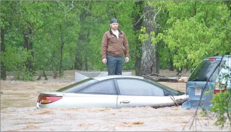  ?? TIMES photograph by Annette Beard ?? Jaxon Douglass, 21, waits patiently for water rescue personnel to reach him as he stands on concrete blocks outside his grandparen­ts’ home on Rustic Drive Wednesday morning. His uncle was swept away in the water and was also rescued safely.