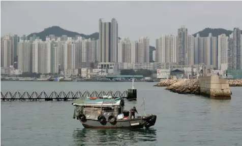  ?? — Reuters ?? A boat sails in front of private and public housing blocks in Hong Kong.