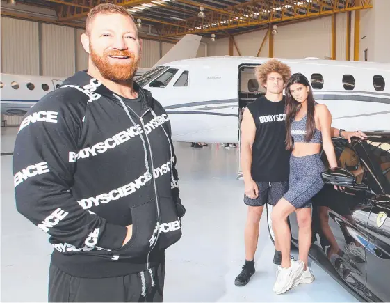  ?? Picture: GLENN HAMPSON ?? Former NRL star Michael Crocker and models Lucciana Beynon and Eloni Vunakece show off the new Body Science activewear.