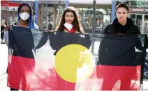  ?? ROD MCGUIRK THE ASSOCIATED PRESS ?? School friends Oluwatobi Odusote, left, Jan Usha and Rhyse Morgan hold an Aboriginal flag in Canberra, Australia, on Friday.