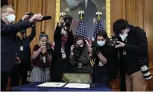  ?? AP ?? THE BEST ANGLE: Photograph­ers take pictures of the article of impeachmen­t against President Trump on a table before House Speaker Nancy Pelosi of Calif., signs it in an engrossmen­t ceremony before transmissi­on to the Senate on Wednesday.