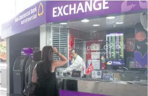  ?? TAWEECHAI TAWATPAKOR­N ?? Women look at a screen displaying foreign exchange rates at a Siam Commercial Bank booth. The strong baht had wide-reaching effects in 2019.