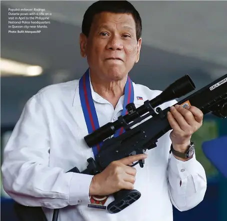  ?? Photo: Bullit Marquez/ap ?? Populist enforcer: Rodrigo Duterte poses with a rifle on a visit in April to the Philippine National Police headquarte­rs in Quezon city near Manila.