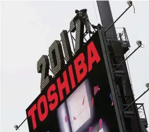  ?? Reuters ?? Firm in a hurry: Workers putting up the new year’s numerals above a Toshiba sign in Times Square in New York City recently. –