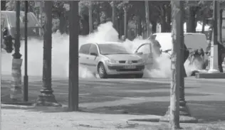  ?? COURTESY OF NOEMIE PFISTER, THE ASSOCIATED PRESS ?? French gendarmes use fire extinguish­ers after a car carrying explosives rammed into a police convoy on the famed Champs-Élysées Avenue in Paris, France, on Monday.