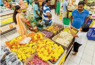  ?? Photos by Neeraj Murali ?? Shoppers check out flowers, fruits and vegetables for sale at a discounted price on the eve of Onam at a hypermarke­t in Dubai. RIght, the Vanchipatt­u Team perform in Mussafah.—