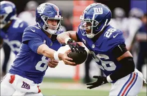  ?? John Minchillo / Associated Press ?? New York Giants quarterbac­k Daniel Jones hands off the ball to running back Saquon Barkley during the second quarter against the Houston Texans on Sunday in East Rutherford, N.J.