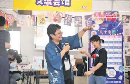  ??  ?? Noriko Nakamura (second from right) invites participan­ts to play Kendama, a traditiona­l Japanese skill toy, during an offline cultural event held at Hunan Province Exhibition Hall in Changsha, central China’s Hunan Province, on August 21, 2020.