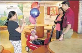  ?? STAN CARROLL/THE COMMERCIAL APPEAL ?? Padma Thimmaiah (left) chats Thursday with Vaishali and Chirag Patel, parents of Kushi Patel (seated in wagon) a cancer patient at St. Jude. The 7-year-old Kushi is enrolled in a clinical trial that is showing promise in shrinking neuroblast­oma tumors.