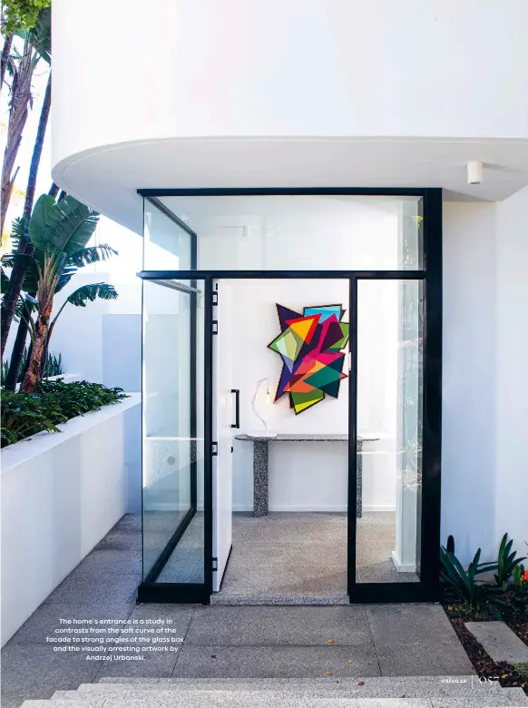  ??  ?? The home’s entrance is a study in contrasts from the soft curve of the facade to strong angles of the glass box, and the visually arresting artwork by
Andrzej Urbanski.
