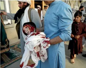  ?? AP ?? An Afghan man holds a bloodstain­ed turban and cap after a bomb attack on a mosque in the Shakar Dara district of Kabul that killed 12 worshipper­s. The attack has so far been the only breach of a three-day ceasefire declared by the Taliban.