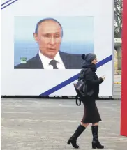  ??  ?? A woman walks past a screen in Sevastopol, Crimea, Feb. 23, 2021.