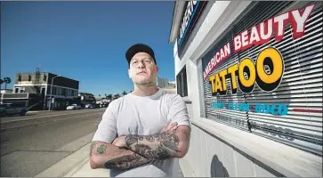  ?? Allen J. Schaben Los Angeles Times ?? JAMES REAL, owner of American Beauty Tattoo in Sunset Beach, said that for years he’s seen groups of L.A. County deputies come in for matching skeleton tattoos — each with a sequential number, more than 100 in all.