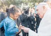  ?? RENE ROSSIGNAUD/AP ?? Pope Francis gives a present to a little girl Sunday during his visit to Malta. The pope prayed for the world to show more kindness and compassion to refugees.