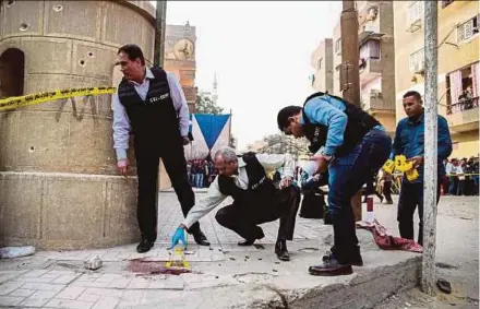  ?? AFP PIC ?? Security members and forensics police at the site of a gun attack outside a church south of Cairo yesterday.