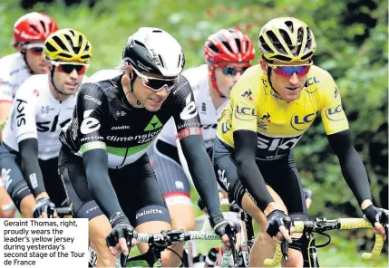  ??  ?? Geraint Thomas, right, proudly wears the leader’s yellow jersey during yesterday’s second stage of the Tour de France