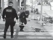  ?? STACEY WESCOTT Chicago Tribune/TNS ?? A police officer picks up a water-logged American flag Tuesday along the parade route.