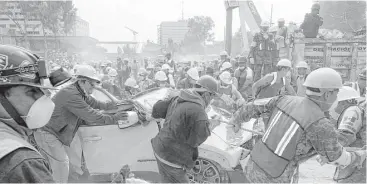  ?? Darío López-Mills / AP ?? Voluntario­s y militares remueven escombros de un vehículo estacionad­o frente a una fábrica de ropa.