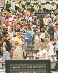  ?? ASSOCIATED PRESS FILE PHOTO ?? Passengers fill rope lines as they make their way to the security checkpoint­s at Hartsfield-Jackson Atlanta Internatio­nal Airport in Atlanta.