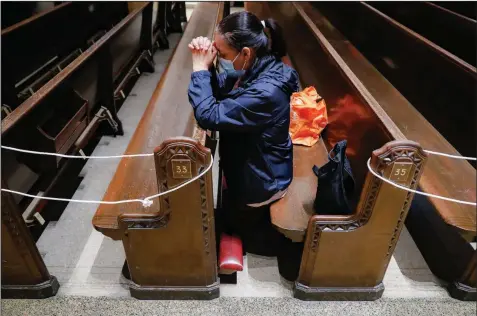  ??  ?? A member of Saint Bartholome­w Roman Catholic Church in Queens, N.Y., prays in the church’s nearly empty pews Monday. (AP/John Minchillo)