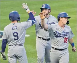  ?? Ashley Landis Associated Press ?? MAX MUNCY and Will Smith greet Gavin Lux after they scored on Matt Beaty’s double in the fourth. The Dodgers scored eight in that inning and five in the fifth.