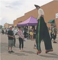  ?? DANIELLE PROKOP/THE NEW MEXICAN ?? A stilt walker talks with Jim and Jan Patterson on Saturday during the 2019 Theatre Walk.