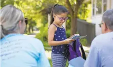  ??  ?? Incoming kindergart­ener Kylie Batiz looks through a new backpack delivered by Stambaugh and Jose Sanchez. The backpack included books, a folder with a informatio­n for parents, a stuffed animal and pencils.