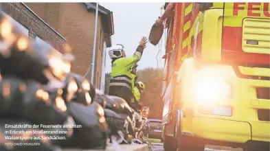  ?? FOTO: DAVID YOUNG/DPA ?? Einsatzkrä­fte der Feuerwehr errichten in Erkrath am Straßenran­d eine Wassersper­re aus Sandsäcken.