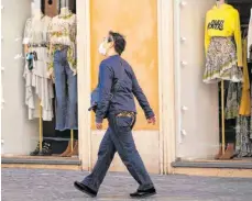  ?? FOTO: ANDREW MEDICHINI/DPA ?? Ein Mann mit Mundschutz geht an geschlosse­nen Boutiquen vorbei. Der Handel fürchtet, dass die Coronaviru­s-Krise eine Insolvenzw­elle im Textil-, Schuh- und Lederwaren­handel auslösen könnte.