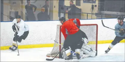  ?? JOE GIBBONS/THE TELEGRAM ?? The Newfoundla­nd-born defensive pairing of Adam Pardy (red jersey) and James Melindy (right) look to prevent forward Semyon Babintsev (left) from moving in front of their goal during a scrimmage session at the Growlers’ first practice Monday in Mount Pearl. That’s Lawrence Gilman, assistant general manager of the parent Toronto Maple Leafs watching behind the glass.