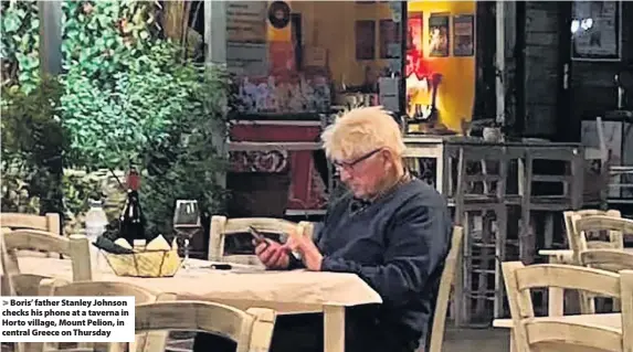  ??  ?? > Boris’ father Stanley Johnson checks his phone at a taverna in Horto village, Mount Pelion, in central Greece on Thursday