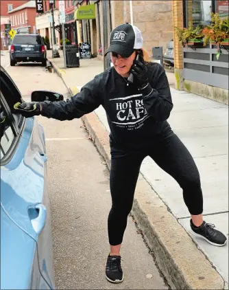  ?? ‘DANA JENSEN/THE DAY ?? Bartender/assistant manager Jodi Alberti takes a take-out order over the phone while taking cash for an order curbside Thursday in front of Hot Rod Café in New London.