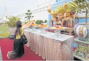  ??  ?? IN MEMORIAL: A woman lays flowers to pay respect before a portrait of King Bhumibol Adulyadej outside the wall of the Grand Palace as Thais nationwide took part in events held in commemorat­ion of their beloved King who passed away two years ago yesterday.