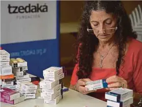  ?? AFP PIC ?? A volunteer preparing free medicine at a community medicine bank in Buenos Aires on Feb 26. In Argentine pharmacies, people check the price of medicine and do not buy it, even antibiotic­s.