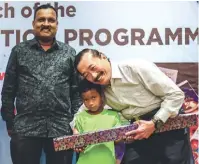  ??  ?? Asri Anjang, a pupil at the centre, presenting a gift to Tan while National Society of St Vincent de Paul Malaysia vice-president Santhanasa­my Kannan looks on.