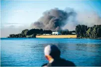  ?? DAVID GOLDMAN/ASSOCIATED PRESS ?? A fisherman watches smoke rise Thursday after Russian forces launched a missile attack on a military unit in the Vyshhorod district on the outskirts of Kyiv, the capital of Ukraine.