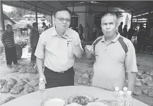  ??  ?? SEDAP: Ketua Kaum Kampung Sebuak Amit Bakeri (kanan) bersama Lo (kiri) menikmati sup daging lembu korban yang baharu sahaja dimasak di Surau Darul Alamin di Kuching.