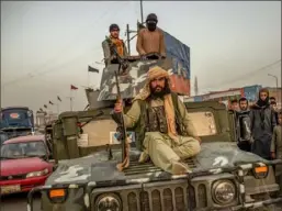  ?? Jim Huylebroek/The New York Times ?? Taliban fighters ride on a Humvee in Kabul, Afghanista­n, Sunday after the group completed its takeover of the Afghan capital and government.