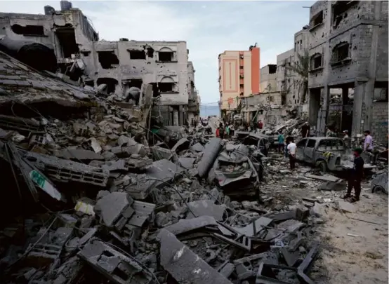  ?? ADEL HANA/ASSOCIATED PRESS ?? Above, people inspected the rubble of a mosque destroyed by an airstrike in Gaza City on Monday. Left, an image from a video on Telegram showed an armed Palestinia­n militant leading away a man during a music festival in Israel.
